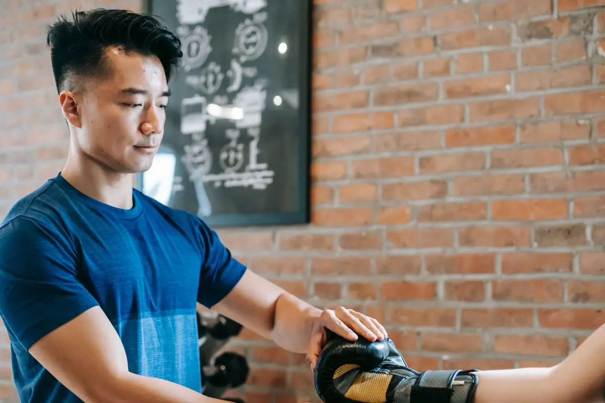 ジムでトレーニング器具を準備するアジア人男性トレーナー(イメージ写真)